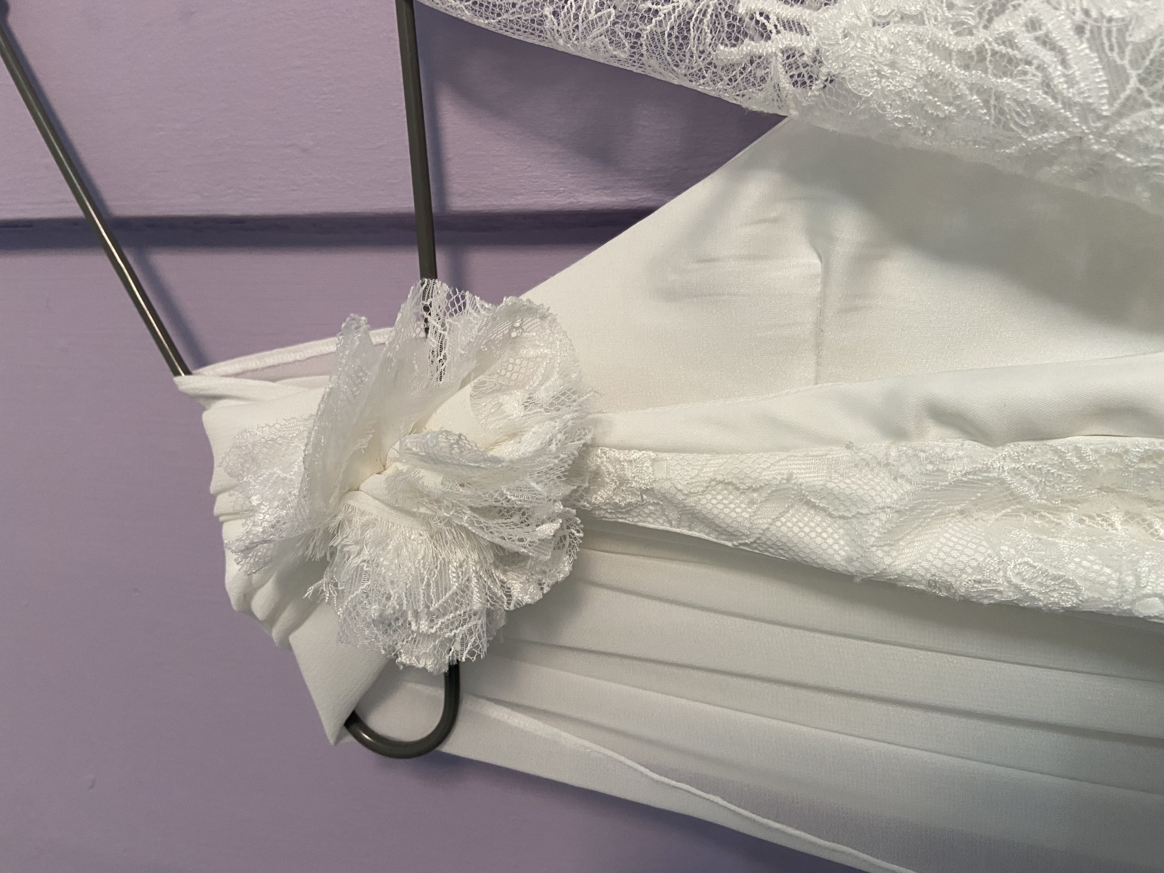 Détail d’une petite fleur de mousseline et dentelle sur la robe de mariée, née d’un dérapage fixé à l’épingle qui a séduit la mariée et sa maman